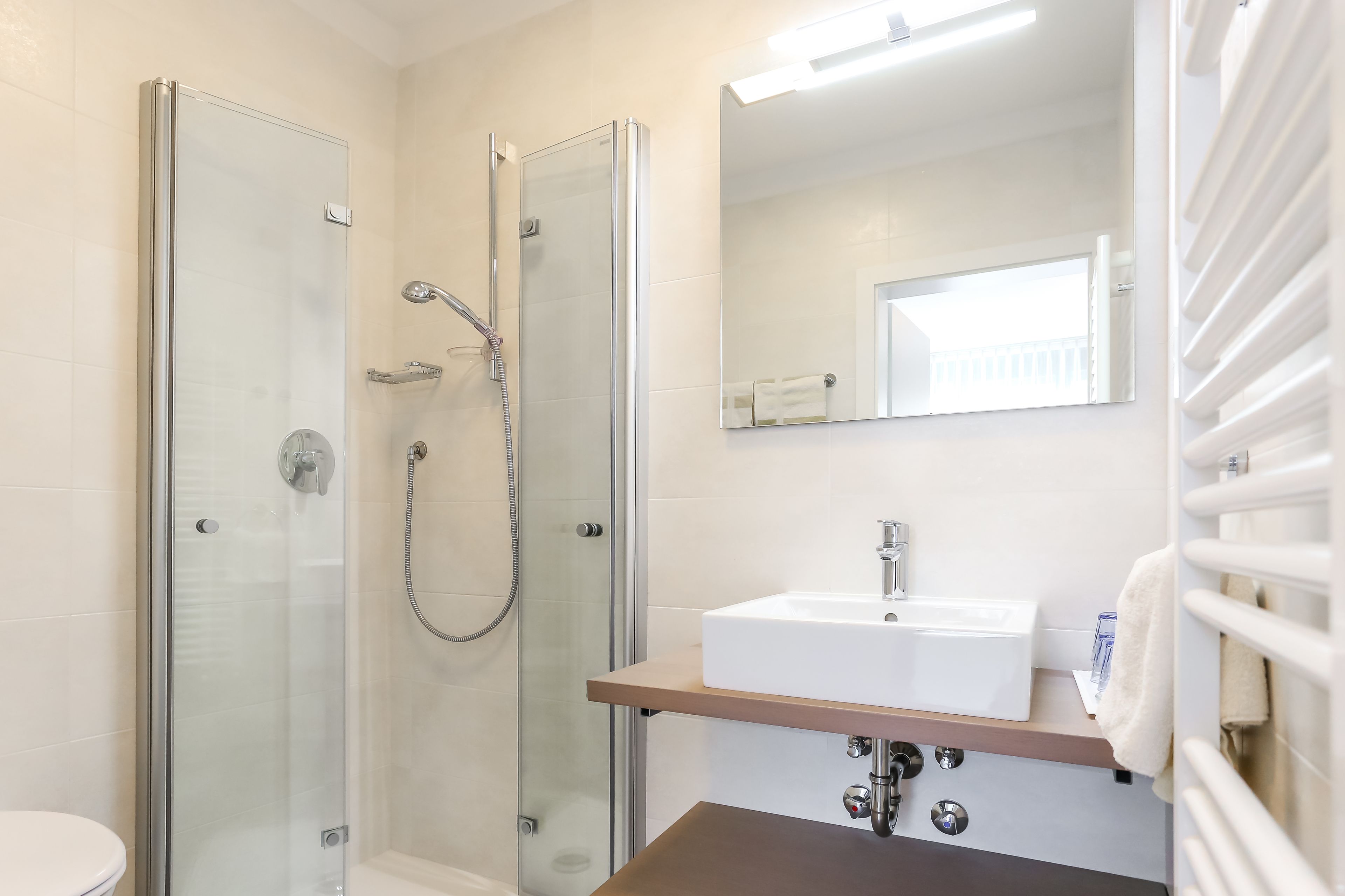 A modern bathroom with a glass-enclosed shower, a white sink, and a mirror above the sink.
