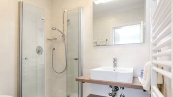 A modern bathroom with a glass-enclosed shower, a white sink, and a mirror above the sink.