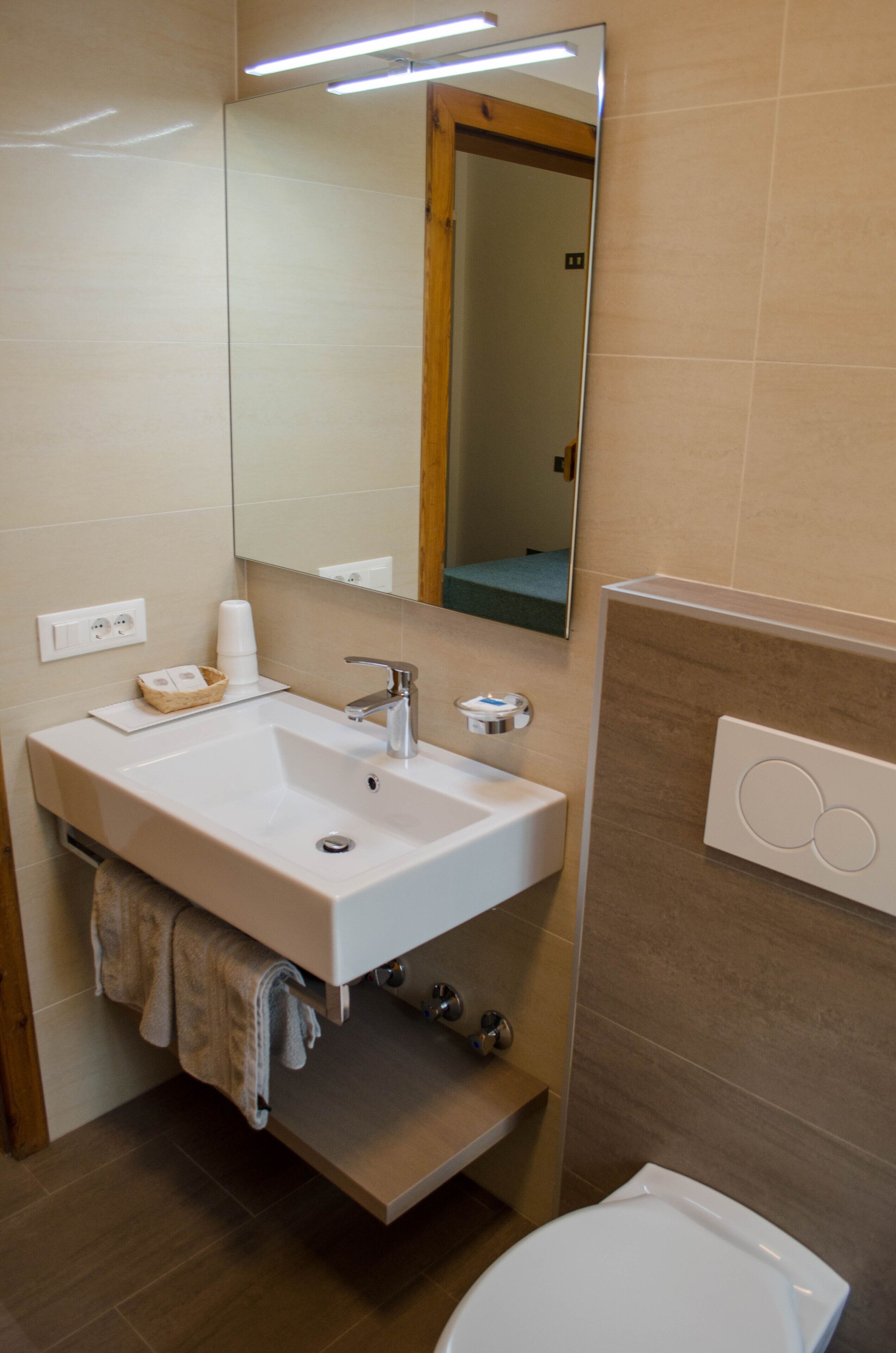 Un baño moderno con lavamanos, espejo y retrete blancos.