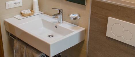Un baño moderno con lavamanos, espejo y retrete blancos.