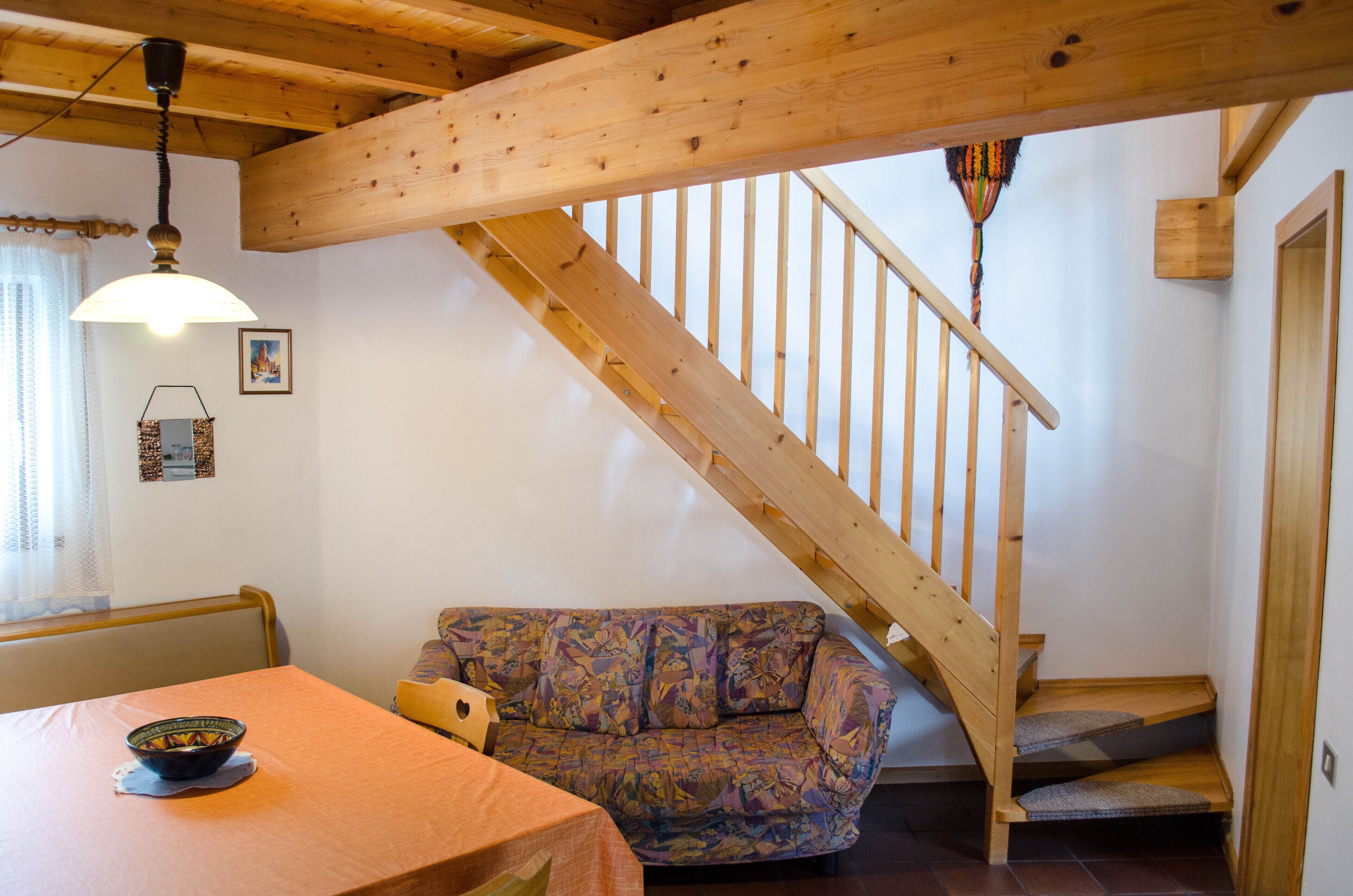 A wooden staircase with a wooden handrail and steps, leading to a landing.