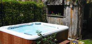 A hot tub in a backyard with wooden walls and a small garden area. - Garni Meinrad (Ora)