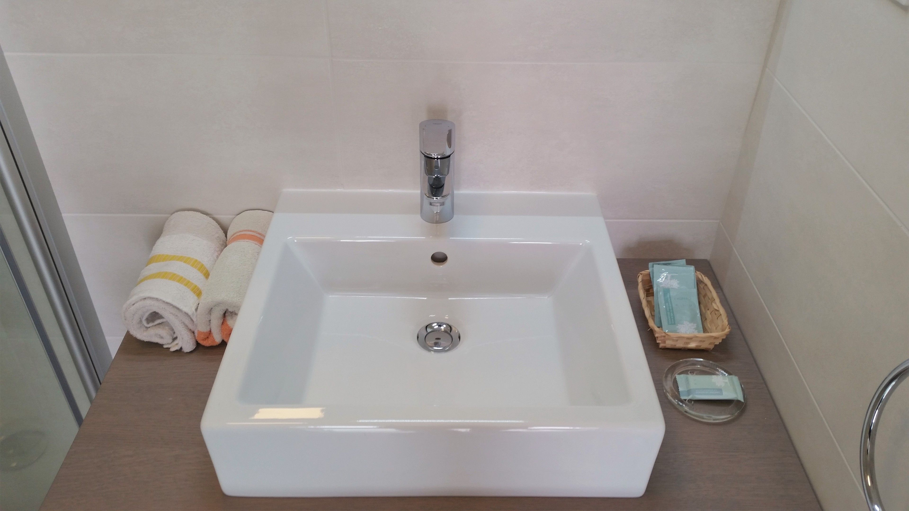 A bathroom with a white sink, a mirror, and a towel rack with towels.