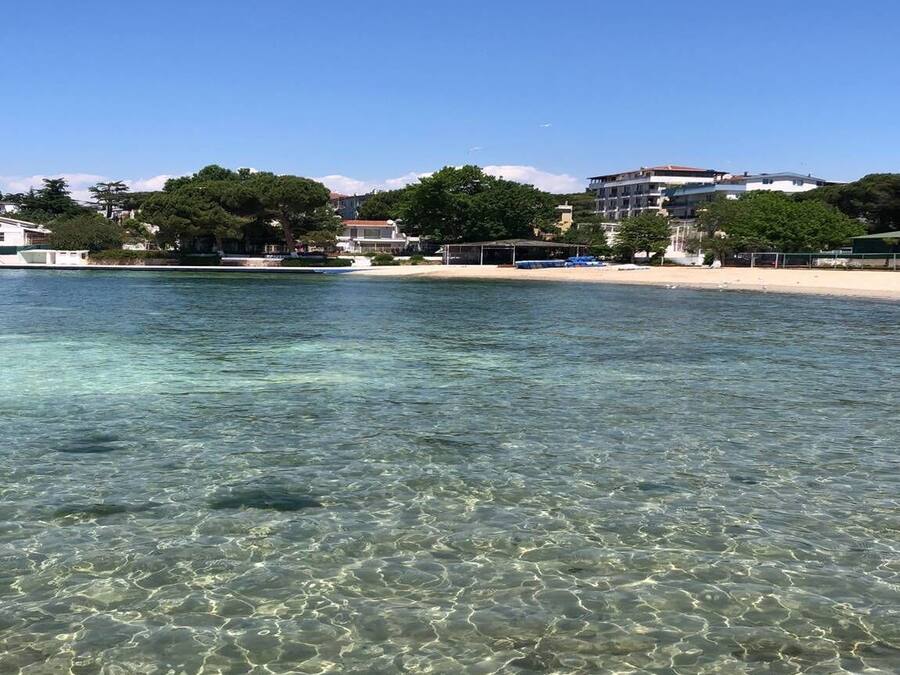 Una playa despejada con orilla de arena y edificios al fondo.