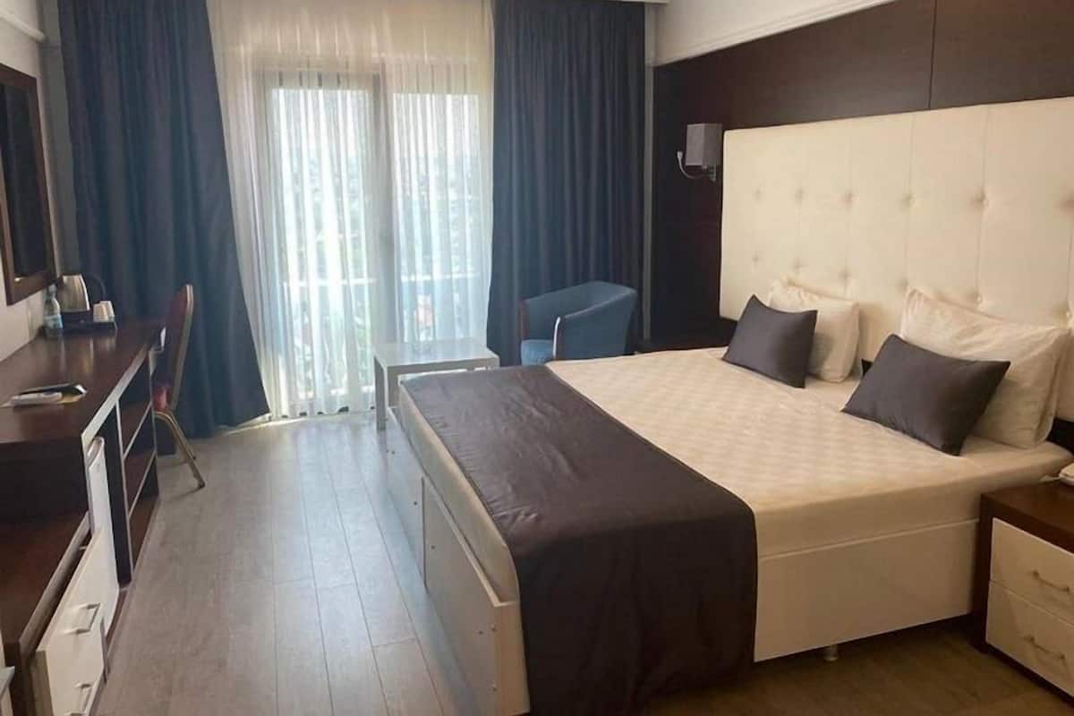 Une chambre d’hôtel avec un grand lit, un bureau et une chaise.