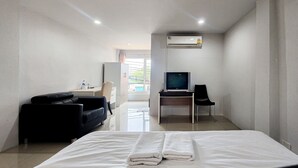 Een hotelkamer met een bed, een bureau met een computer, een stoel, een bank en een airconditioning.
