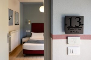 Una habitación de hotel con una cama, un interruptor de luz en la pared y una puerta con un letrero de número.