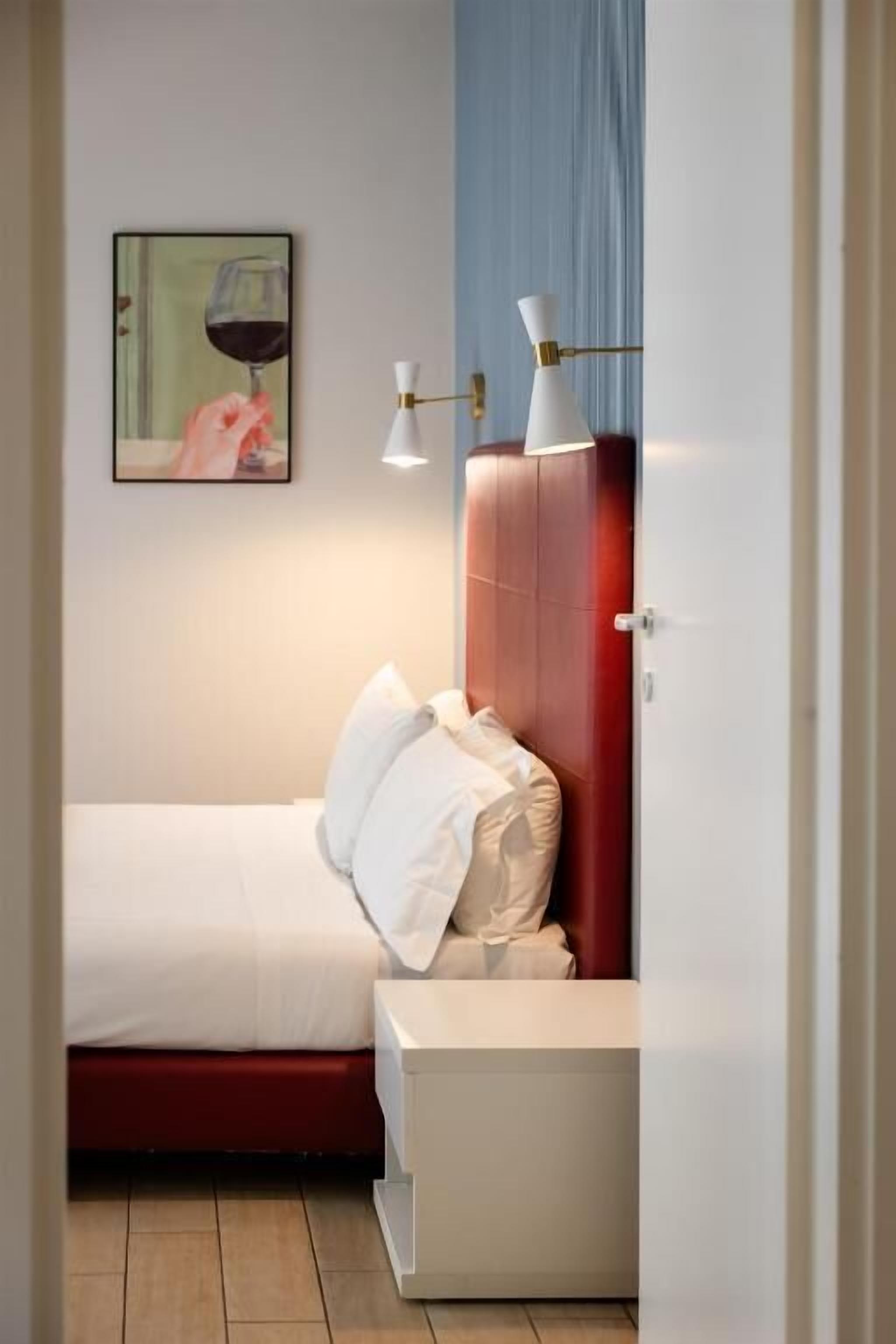 Ein Schlafzimmer mit einem Bett, einem Nachttisch, einer Wandleuchte und einem gerahmten Bild.