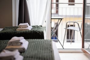A hotel room with two beds, a balcony with a chair, and a view of the outside. - Hotel RossoVino Como (Como)