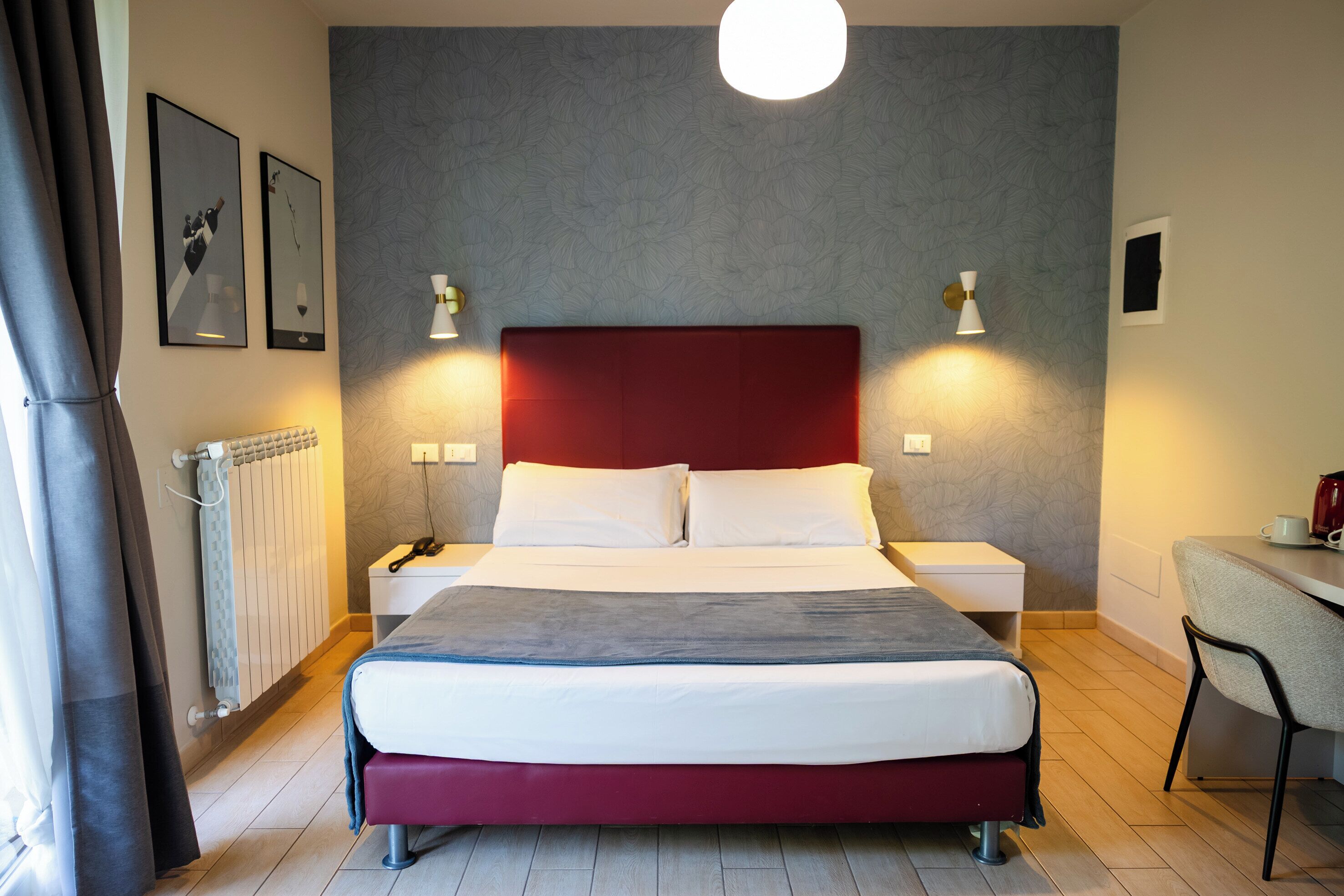 A hotel room with a bed, bedside tables, a desk, and a chair.