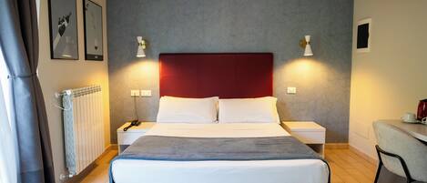A hotel room with a bed, bedside tables, a desk, and a chair.
