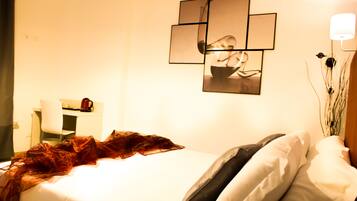 Une chambre d’hôtel comprenant un lit, un bureau avec une chaise, une lampe fixée au mur et un miroir décoratif.