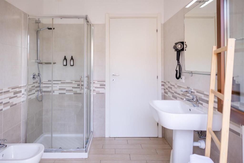 A bathroom with a glass shower enclosure, a white sink, and a mirror.