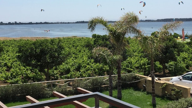 A view of a beach with a clear sky, palm trees, and a few kites flying. - Herons Bay Resort (Marsala)