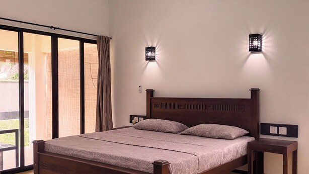 A bedroom with a wooden bed, two bedside tables, and two wall-mounted lights. - Avita Holiday Home (Hikkaduwa)