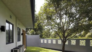 A modern building with large windows, a well-maintained lawn, and a tree in the background. - Avita Holiday Home (Hikkaduwa)