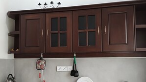 A kitchen with dark wooden cabinets, a kettle, a dish rack, and a sink. - Avita Holiday Home (Hikkaduwa)