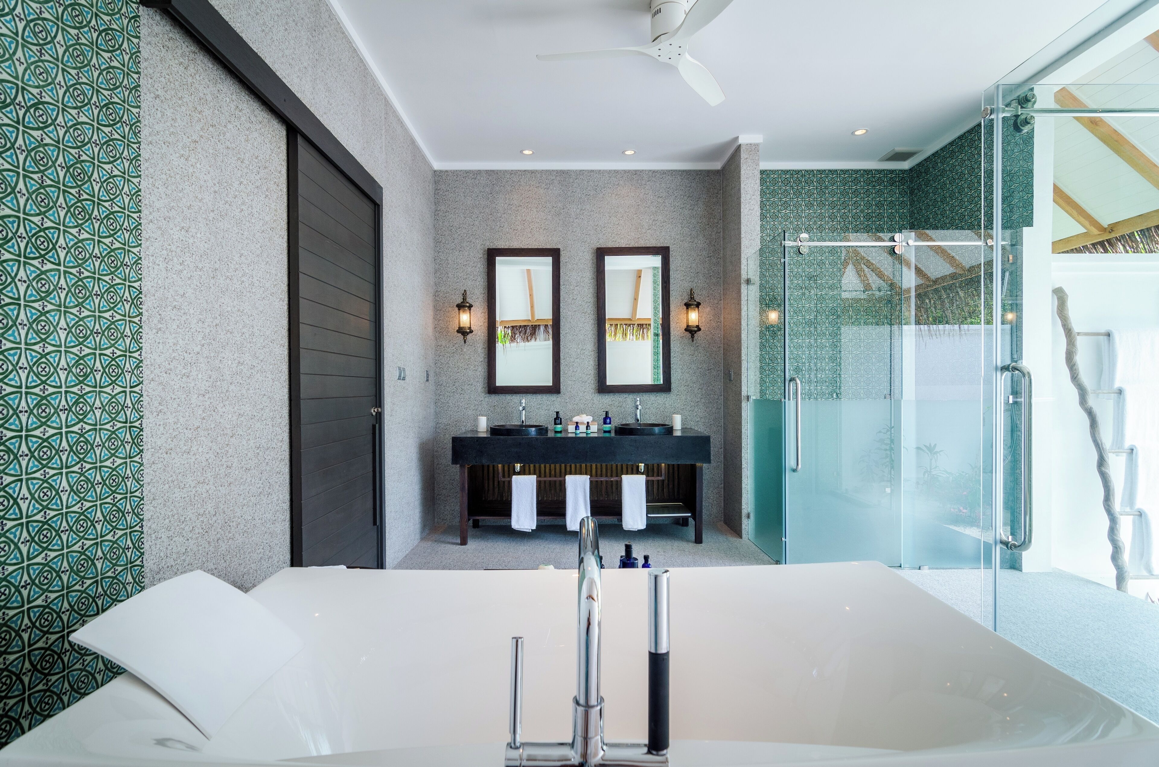 A modern bathroom with a large bathtub, two sinks, and a glass shower enclosure.