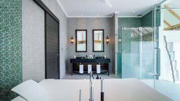 A modern bathroom with a large bathtub, two sinks, and a glass shower enclosure.