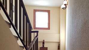 A staircase with a wooden railing, a small statue on the landing, and a window above. - Hostal L Escaleta (Oropesa del Mar)