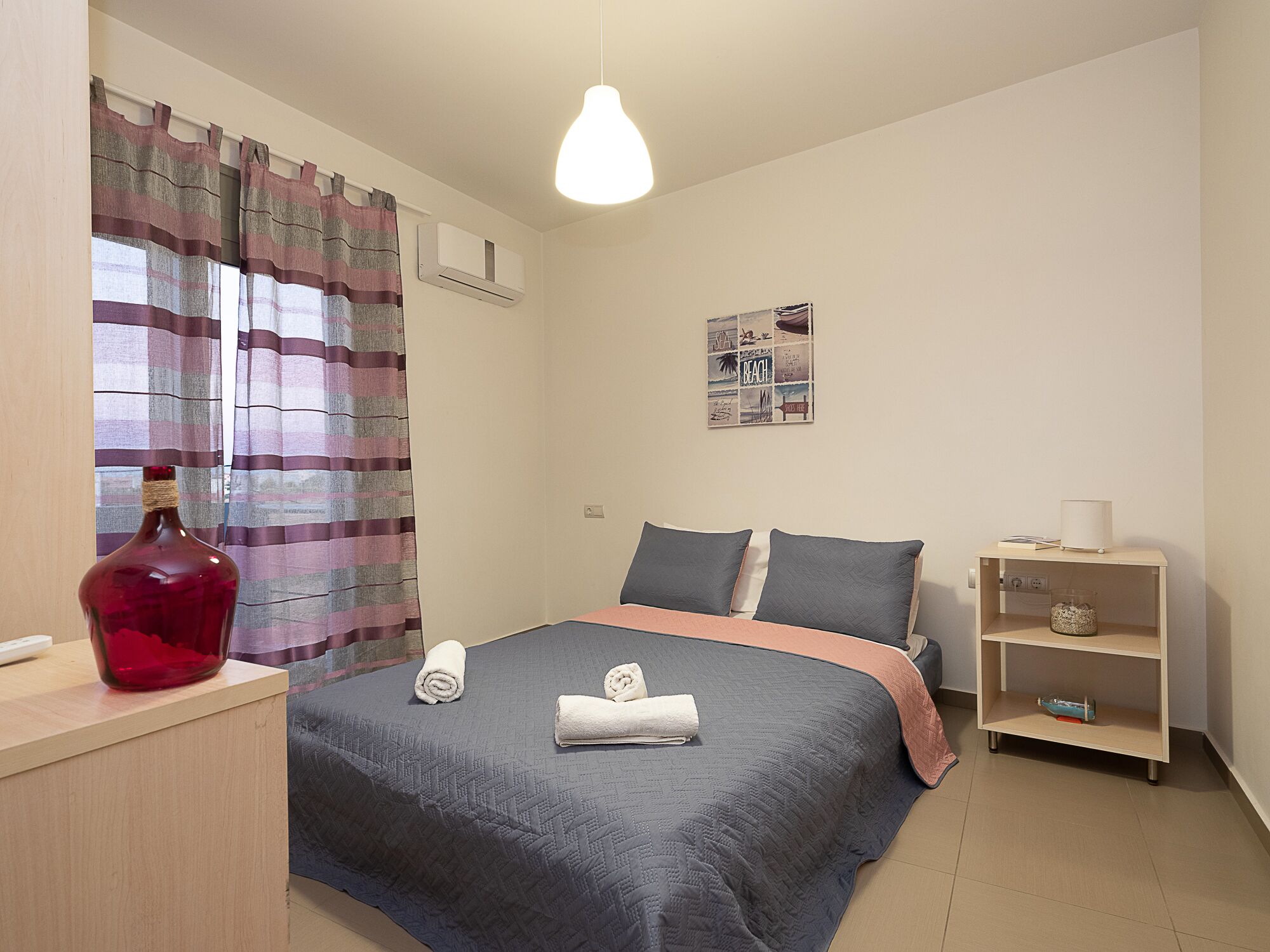 Une chambre à coucher comprenant un lit, une table de chevet, une lampe, une étagère et un élément décoratif mural.