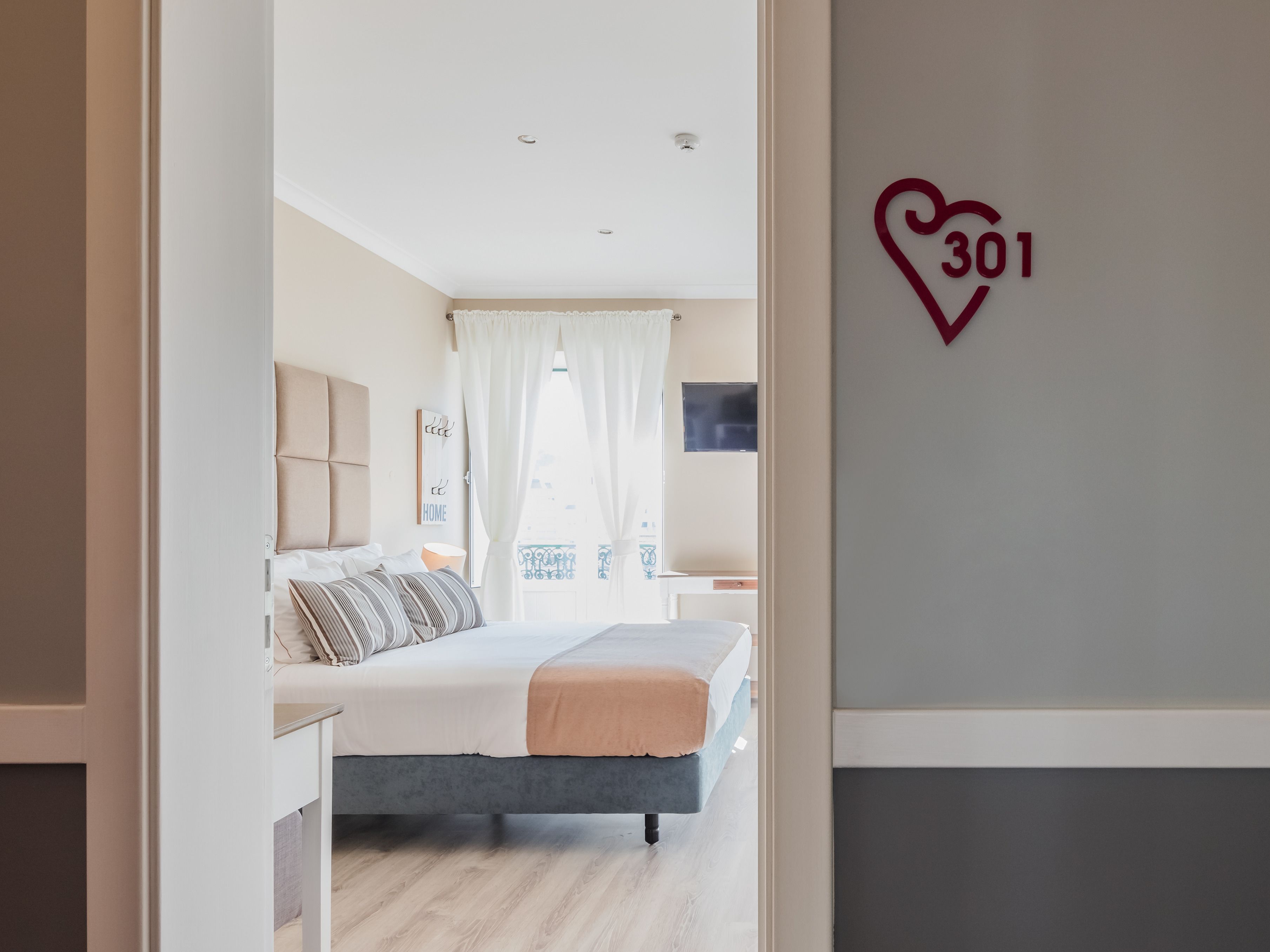 Une chambre moderne avec un lit, une télévision et un mur orné d’un panneau en forme de cœur.