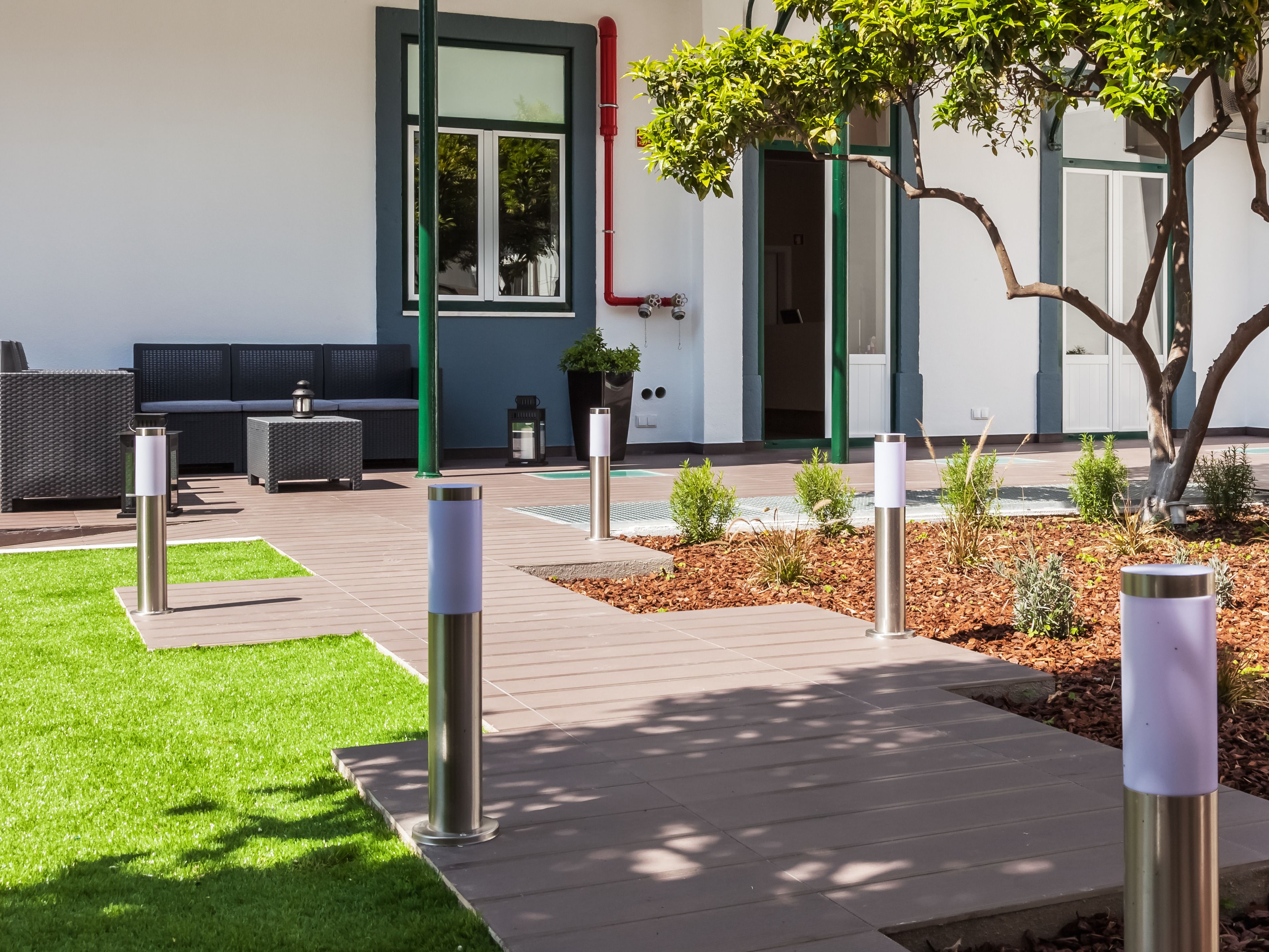 A modern outdoor area with a patio, seating, and a small garden.