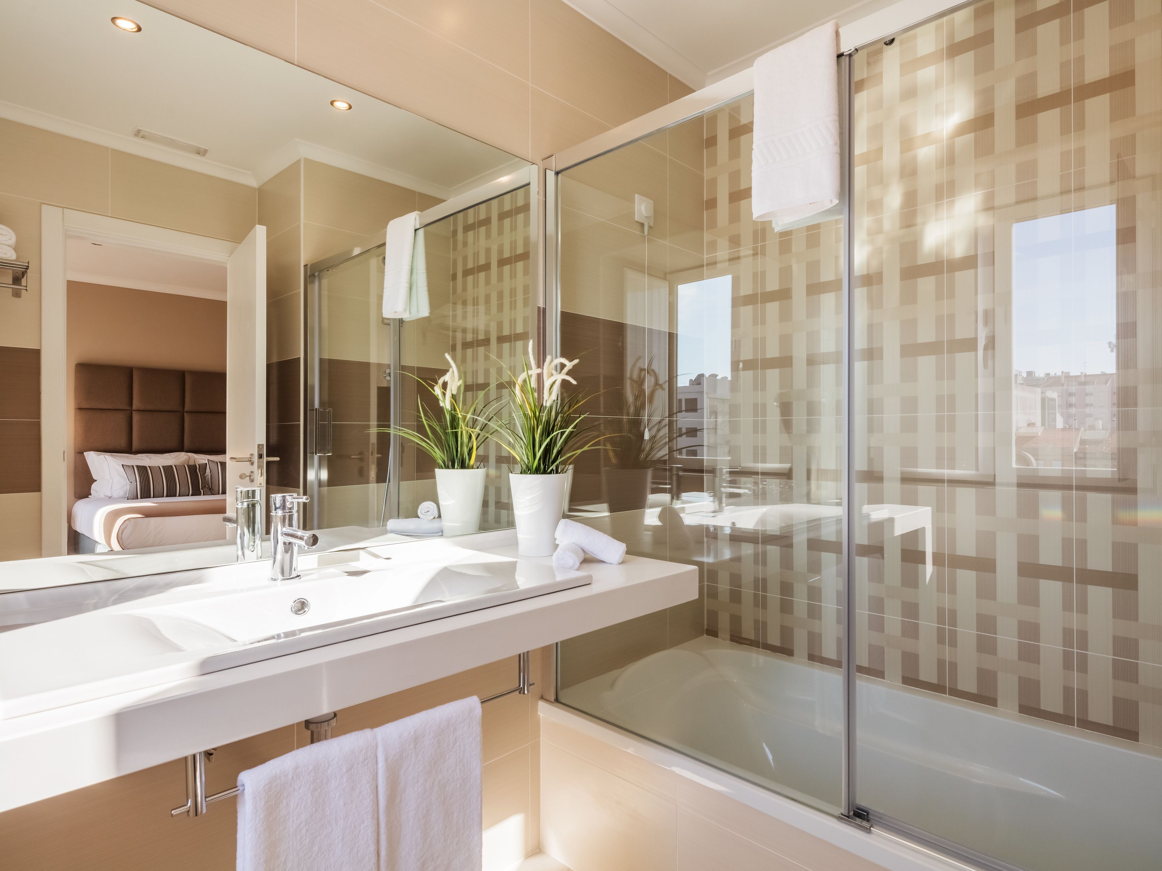 Une salle de bain moderne avec un grand miroir, une douche à l’italienne et une vue sur la ville.
