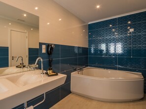 A modern bathroom with two sinks, a large bathtub, and a hairdryer mounted on the wall. - Vila Garden Guesthouse (Lisbon)