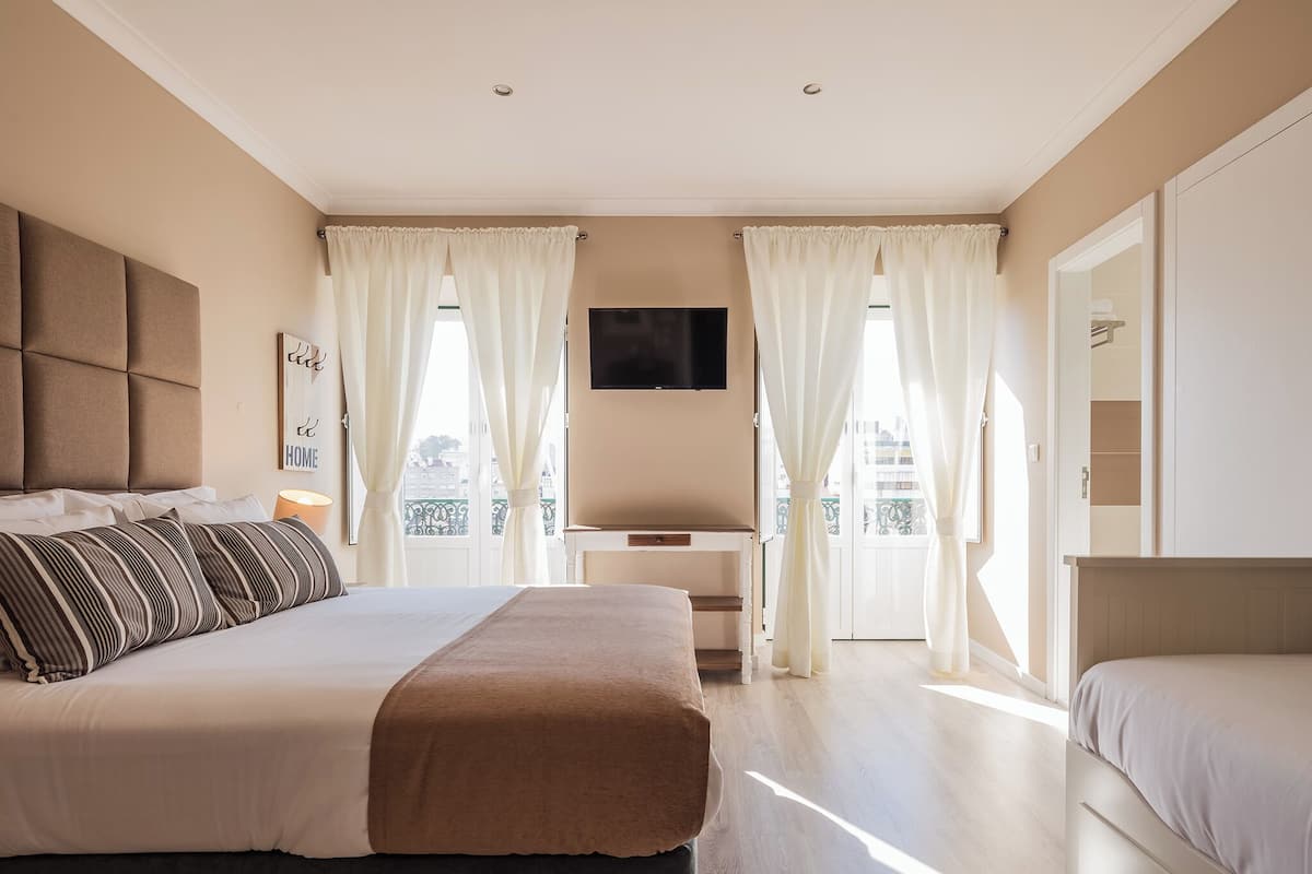 A bedroom with a bed, a desk, and a TV.
