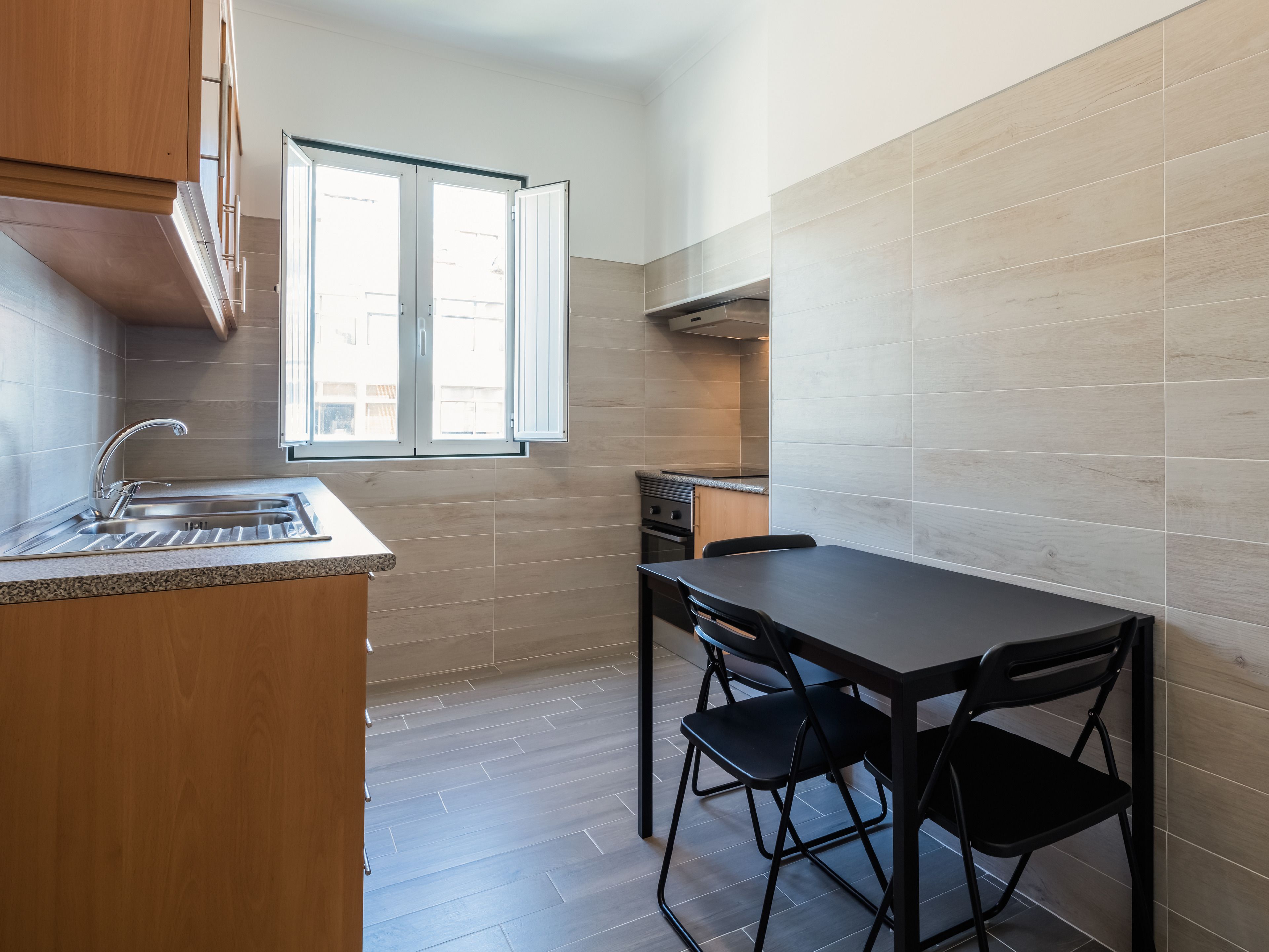 A compact kitchen with a sink, a window, and a dining area with chairs.