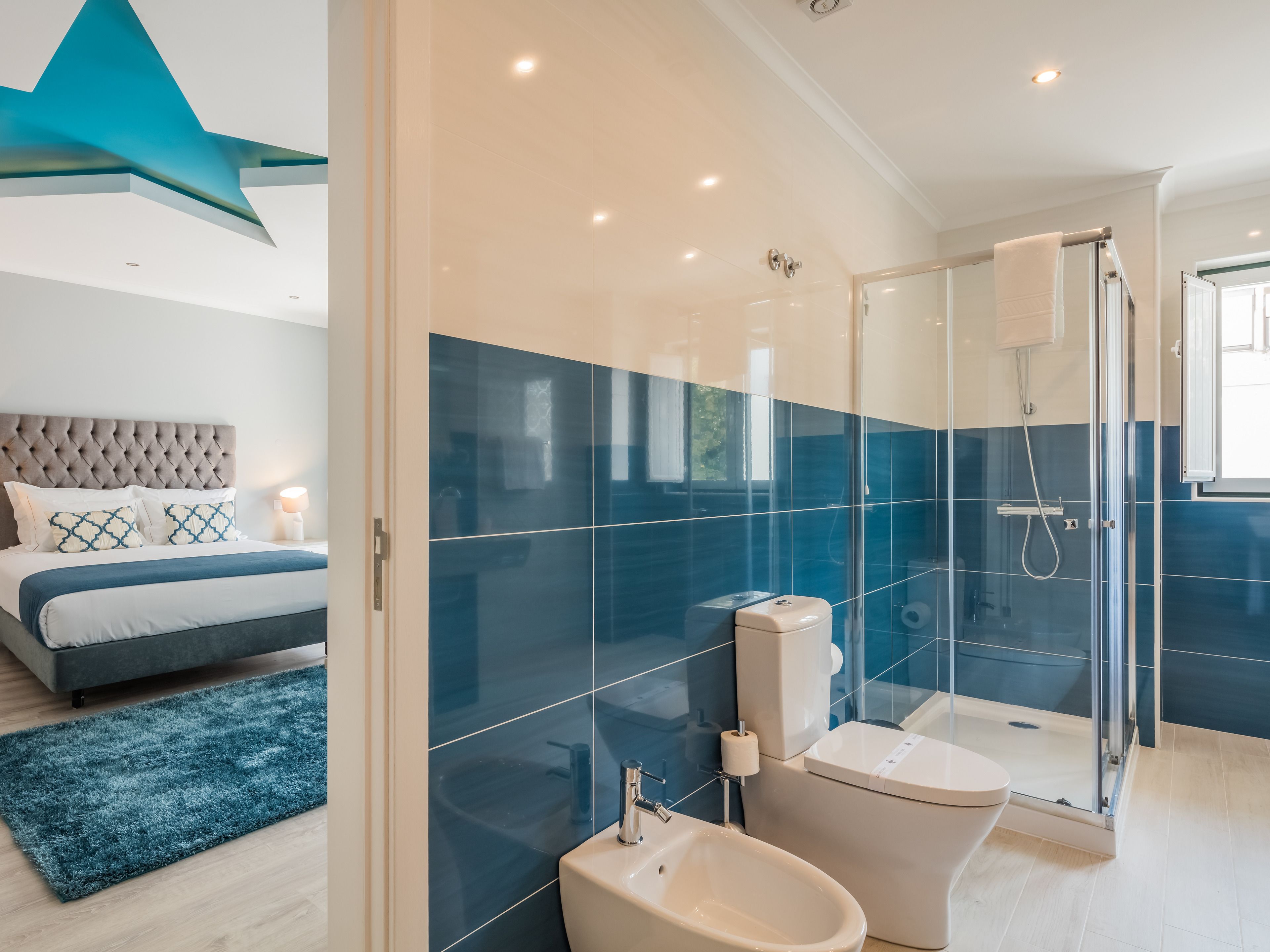 A modern bathroom with a glass shower enclosure, a toilet, and a bidet.