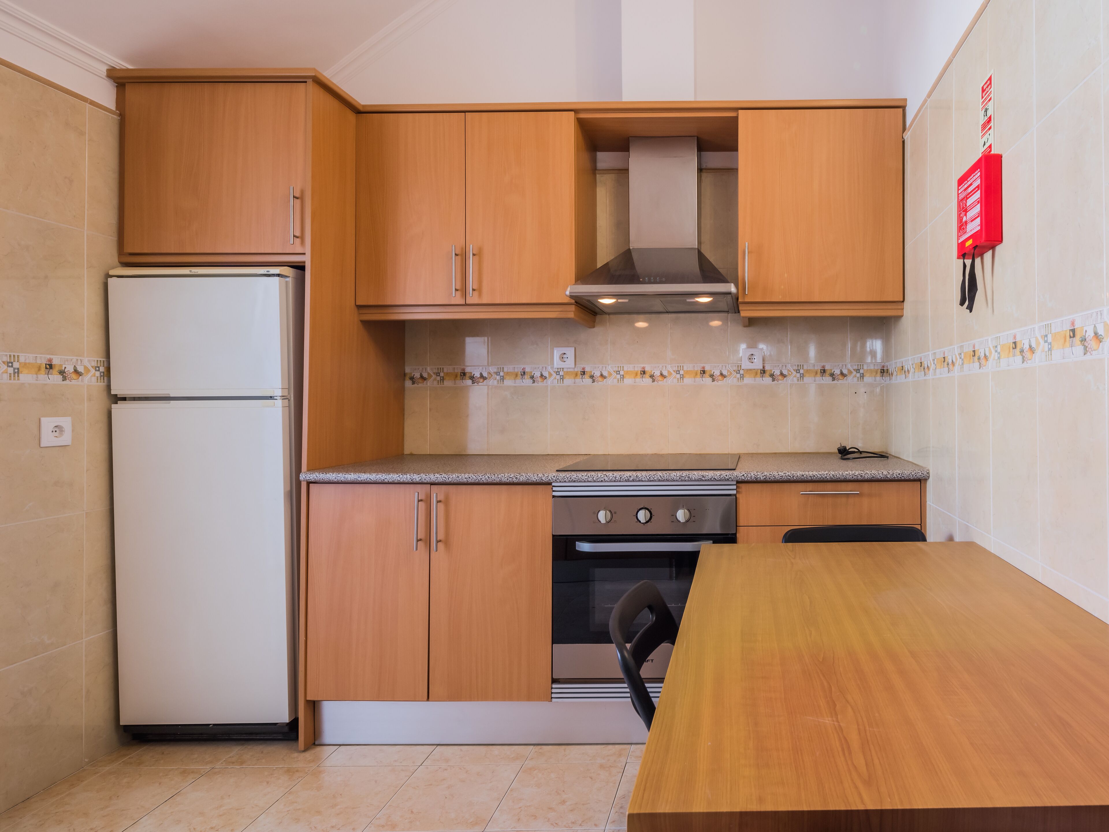 Una cucina compatta con mobili in legno, forno integrato e un piano di lavoro.