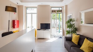 Ein modernes Wohnzimmer mit einer Couch, einem Fernseher, einem roten Schrank und einem großen Fenster.