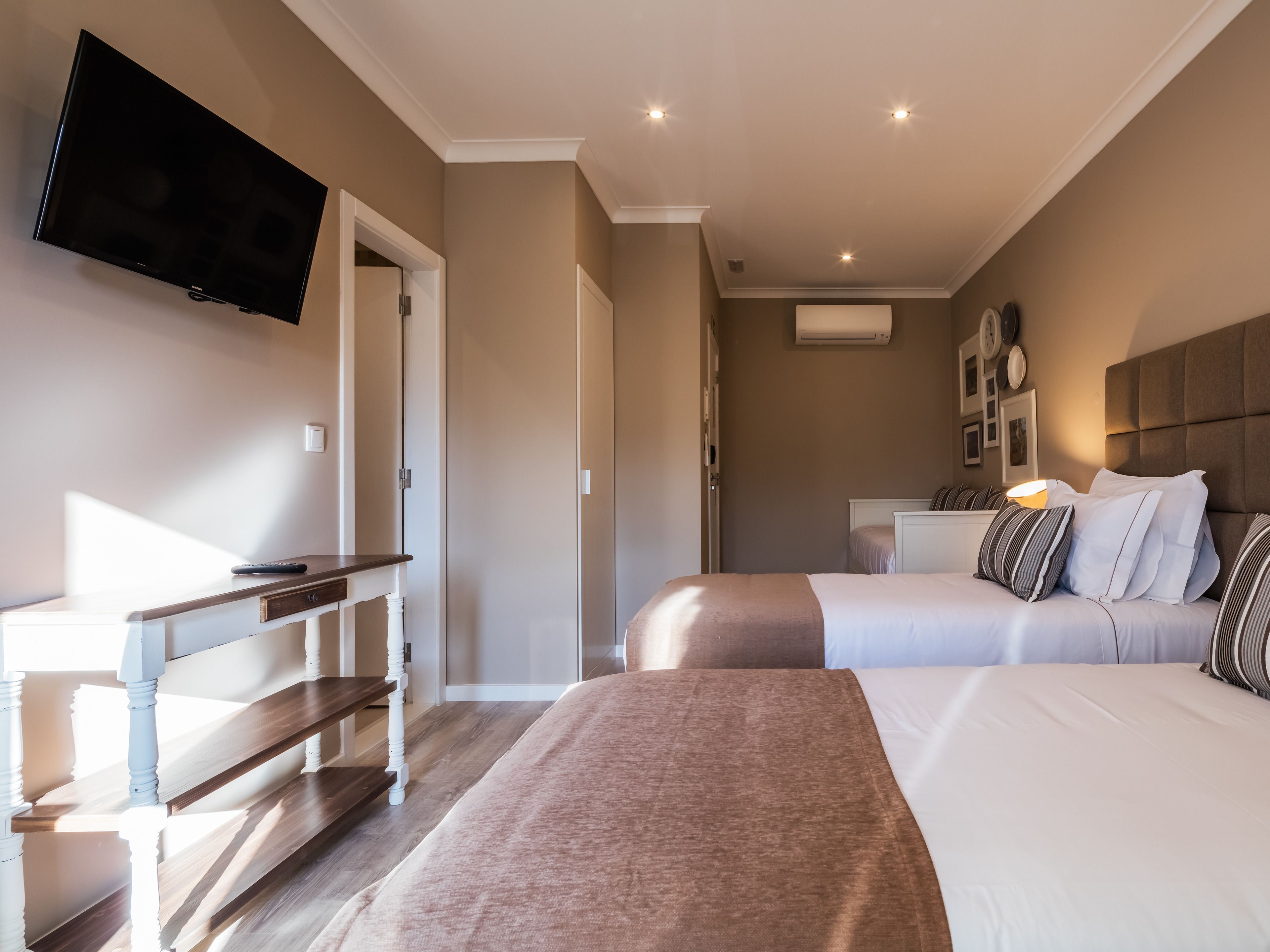 A hotel room with two beds, a TV, a desk, and a wardrobe.