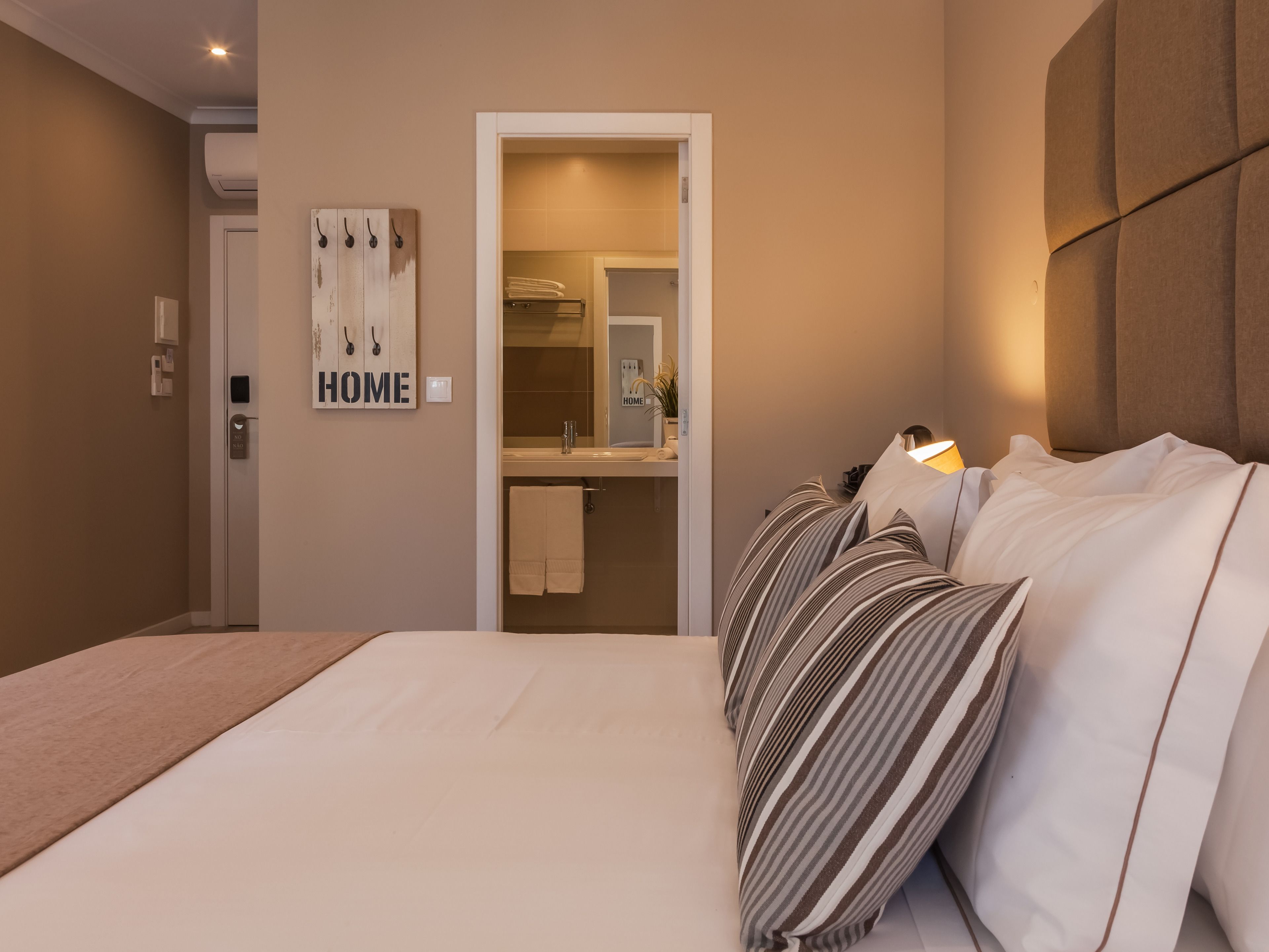 Ein Schlafzimmer mit einem Bett, einem Nachttisch, einem Spiegel und einem an der Wand befestigten Handtuchhalter.