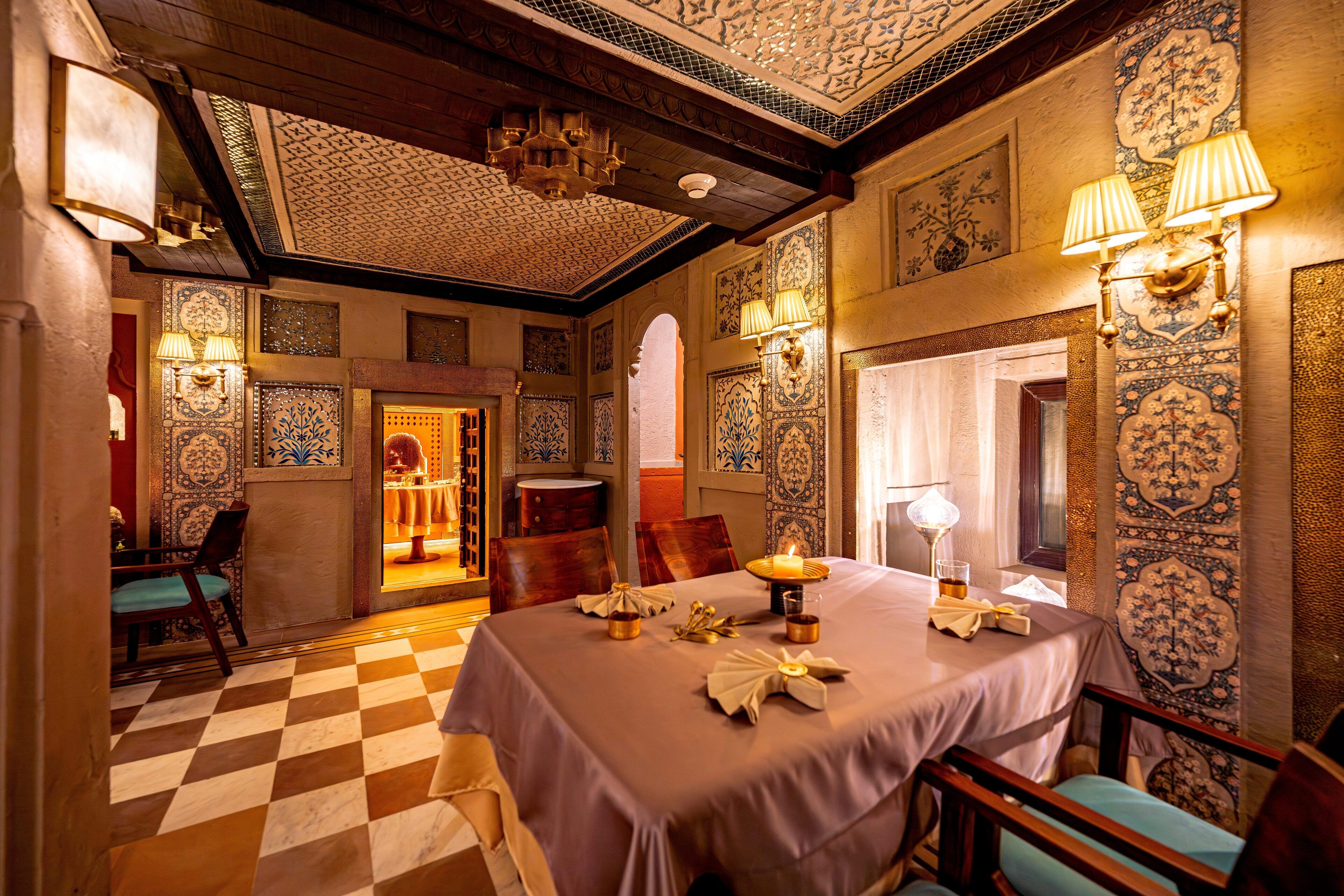A room with a checkered floor, a table set with a candle, and ornate wall decorations.
