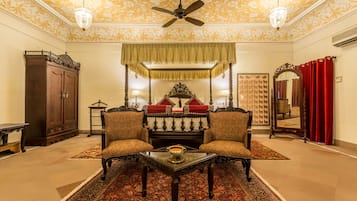 A traditional room with a sofa set, a table, a ceiling fan, and patterned walls.