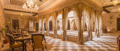 Ein luxuriöses Zimmer mit aufwendiger Decke, Schachbrettboden und traditionellen Möbeln.