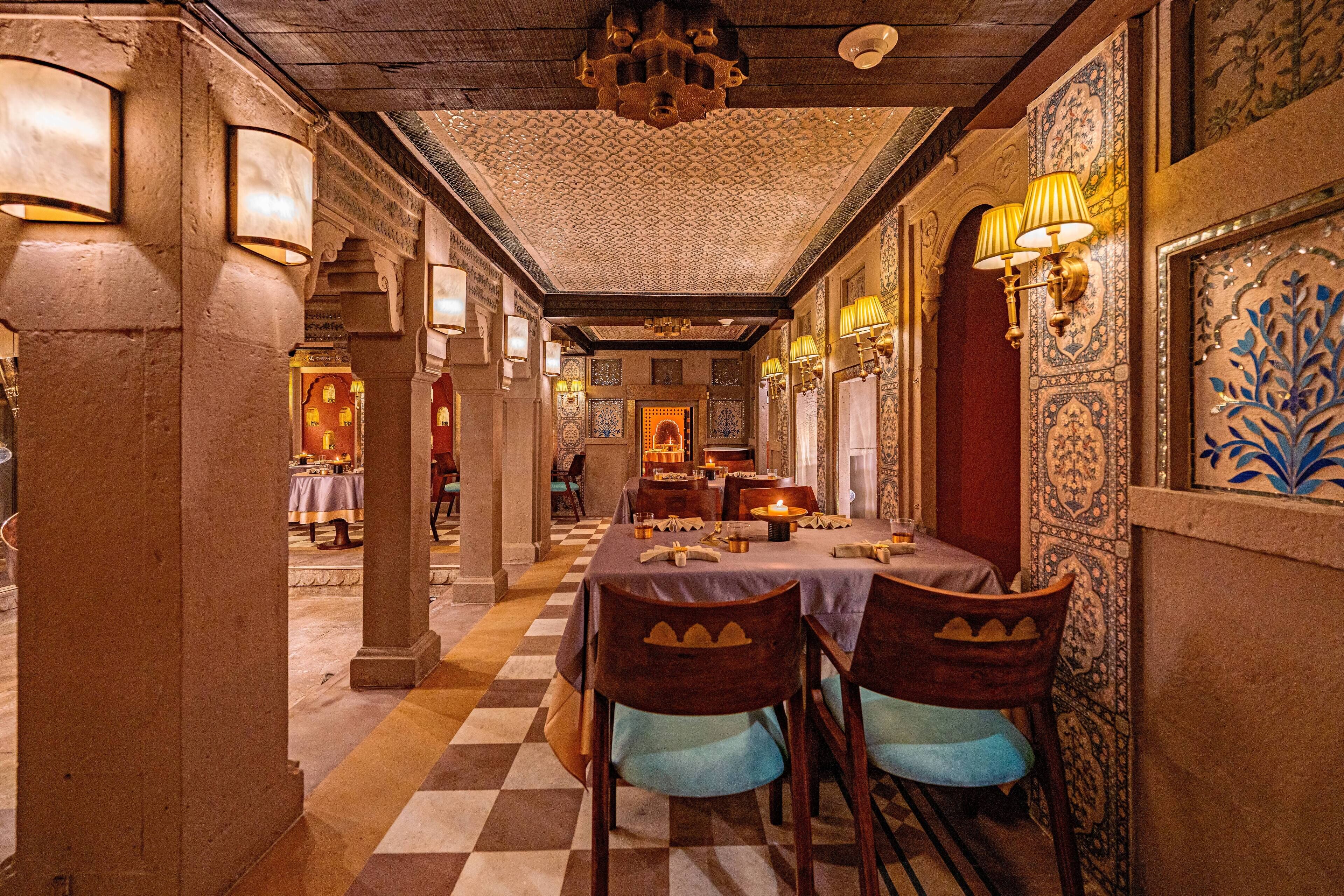 A dining area with checkered flooring, wooden chairs with cushioned seats, and patterned walls.