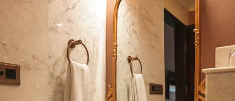 A bathroom with a marble sink, a gold-framed mirror, and a towel rack.