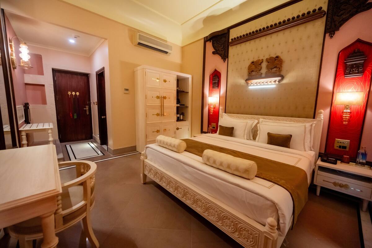 A bedroom with a bed, bedside tables, a wardrobe, and a desk with chairs.