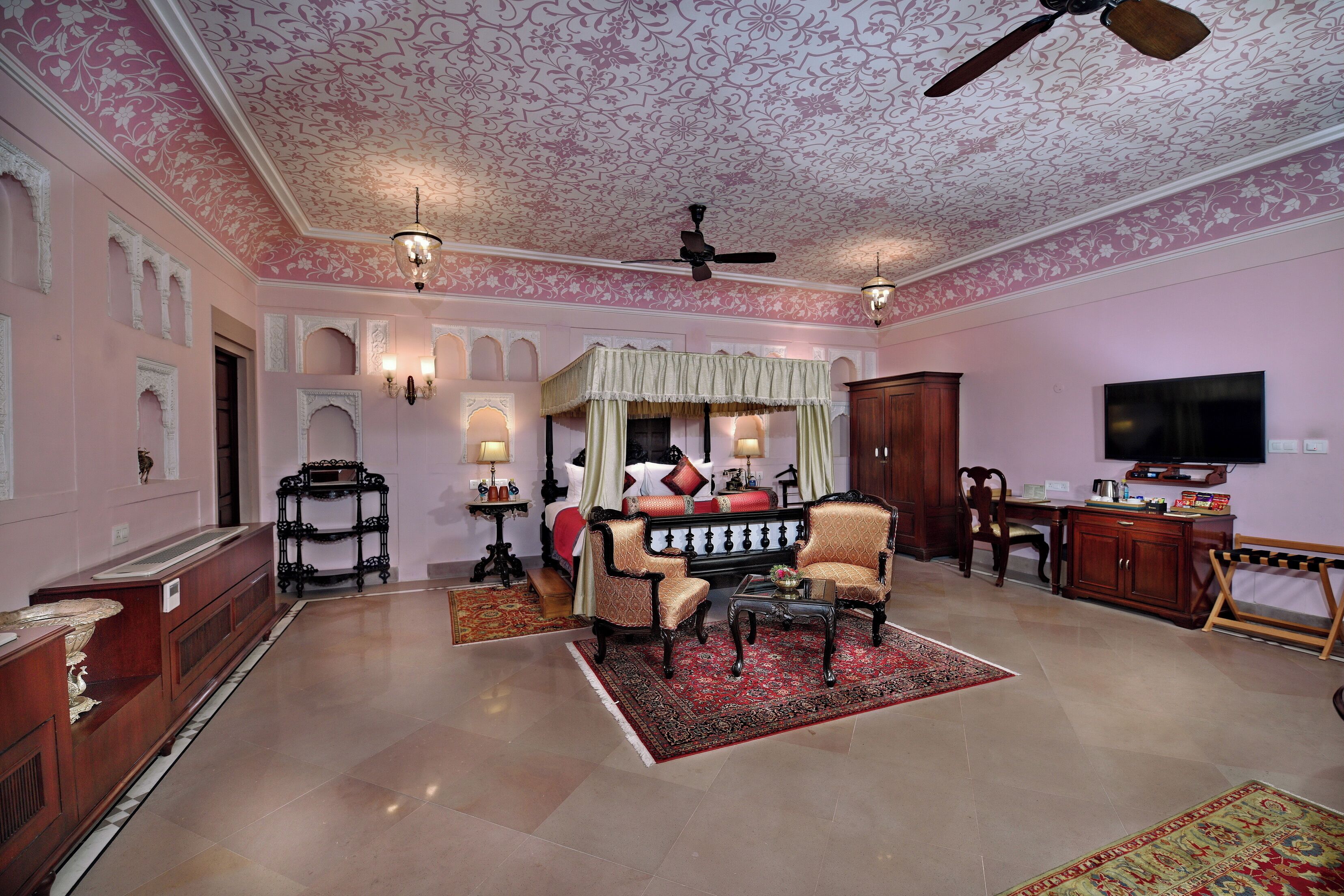 A spacious living room with a large bed, a television, and a ceiling fan.