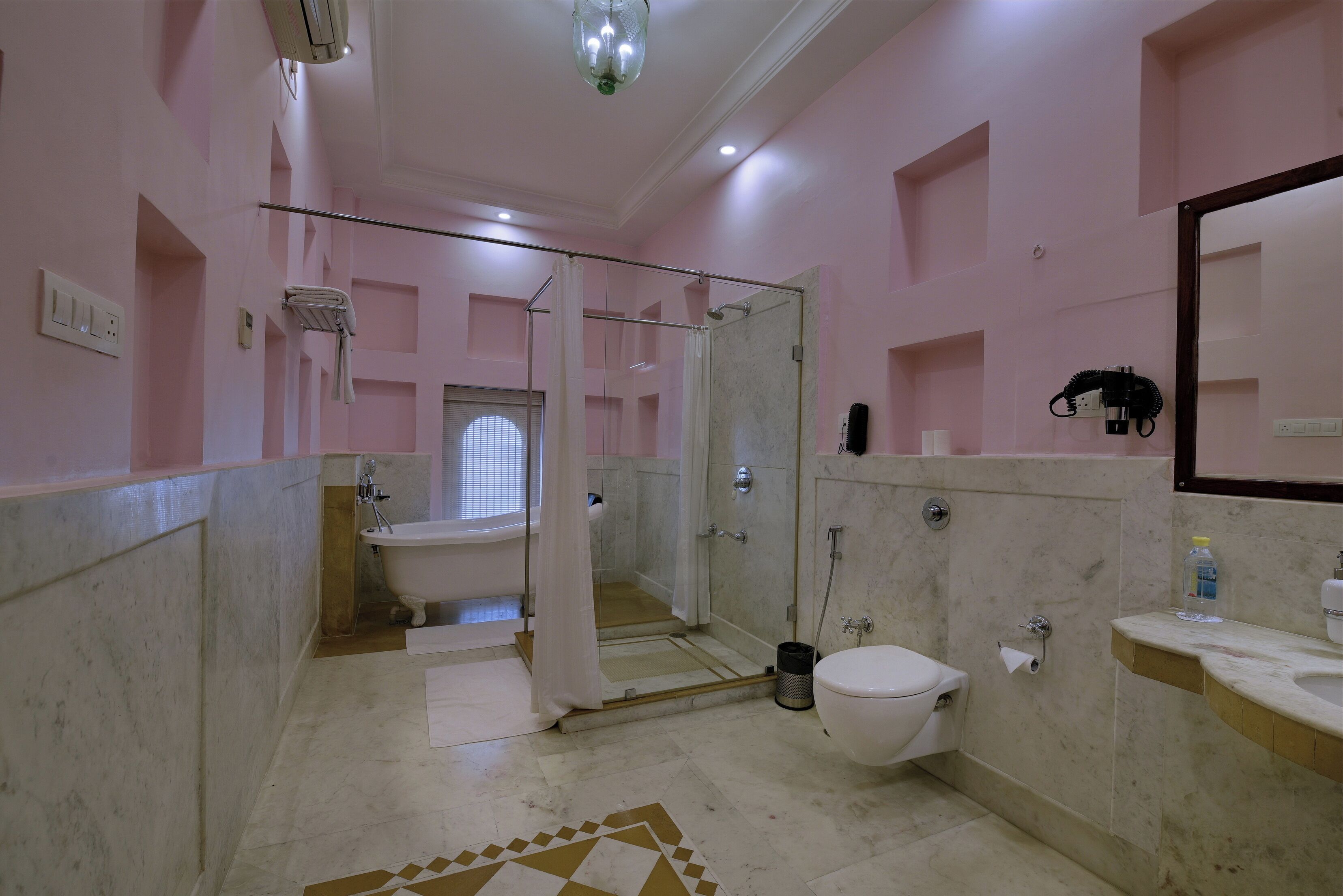 A bathroom with a glass shower enclosure, a bathtub, a toilet, and a sink.