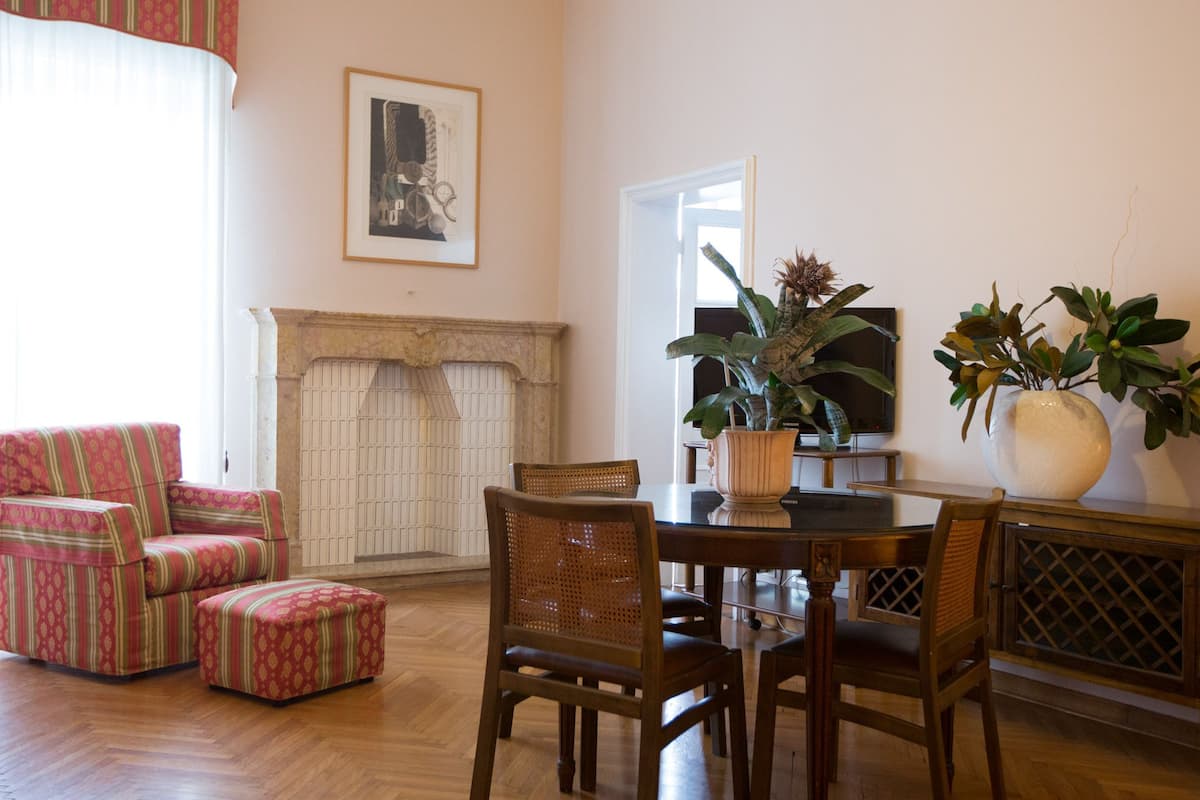 A living room with a fireplace, a dining table with chairs, and two armchairs.