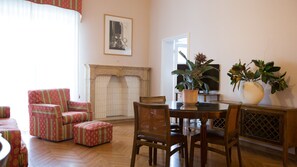 A living room with a fireplace, a dining table with chairs, and two armchairs. - Residence Hotel Castelvecchio (Verona)
