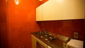 A compact kitchen with red tiles, stainless steel appliances, and white cabinets. - Residence Hotel Castelvecchio (Verona)
