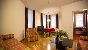 A living room with a sofa, armchair, and a dining table with chairs. - Residence Hotel Castelvecchio (Verona)