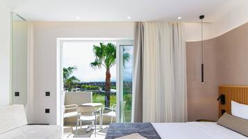 Una habitación de hotel moderna con una cama, un sofá, un balcón con vistas a palmeras y una puerta corredera de cristal.
