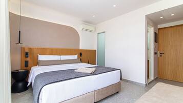Un dormitorio moderno con una cama grande, una mesita de noche, un equipo de aire acondicionado y una puerta de madera.